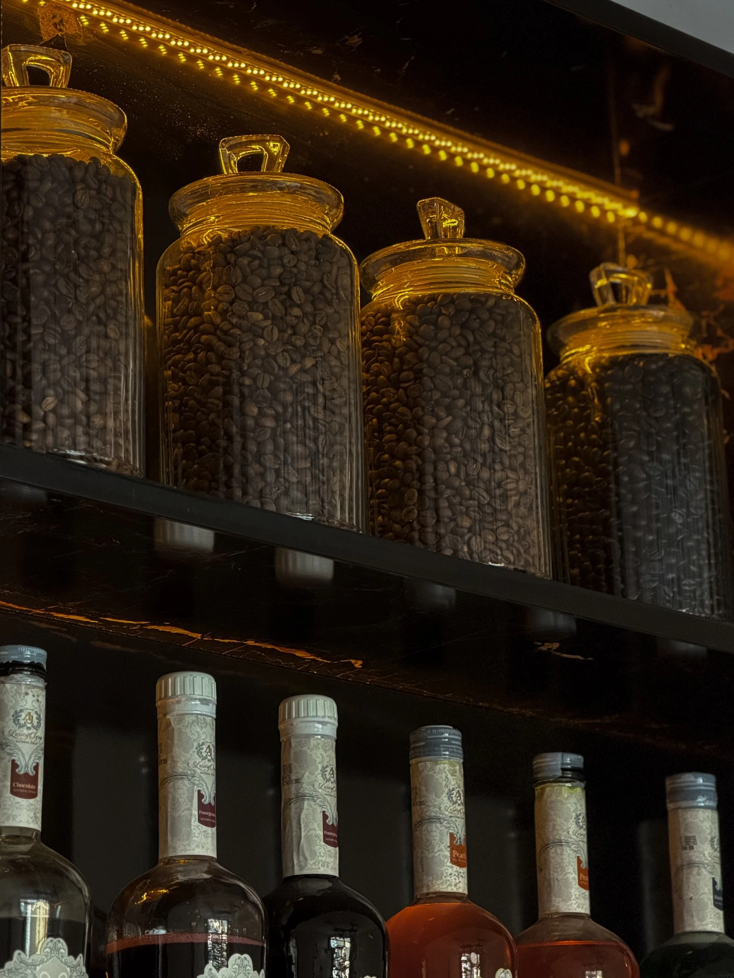Glass jars of coffee beans and syrup bottles on the Aroma Cafe bar