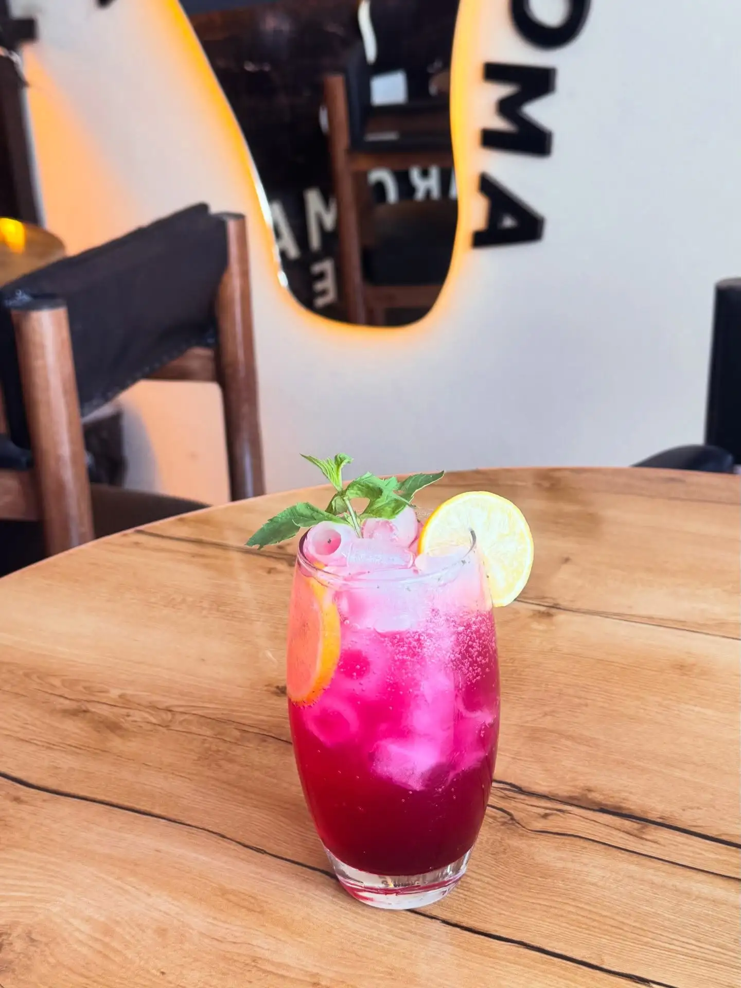 Red berry mojito with mint and lemon on a wooden table